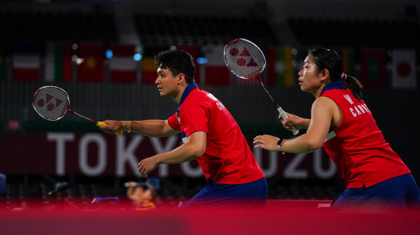 Two badminton players prepare to receive a serve in a mixed doubles game 