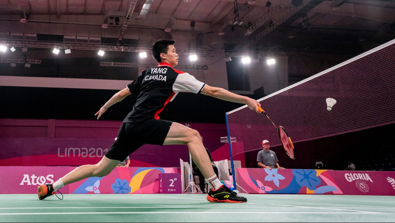 Brian Yang underhands the shuttlecock near the badminton net