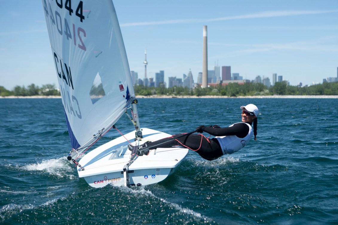 Sarah Douglas leans out over the water as she steers her sailboat on a lake