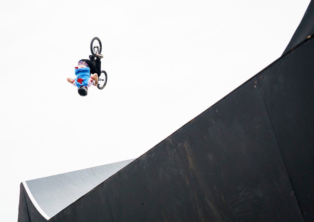 BMX Freestyle competitor does a flip on his bike over a ramp 