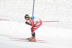 Cross country skier in red suit glides on a course