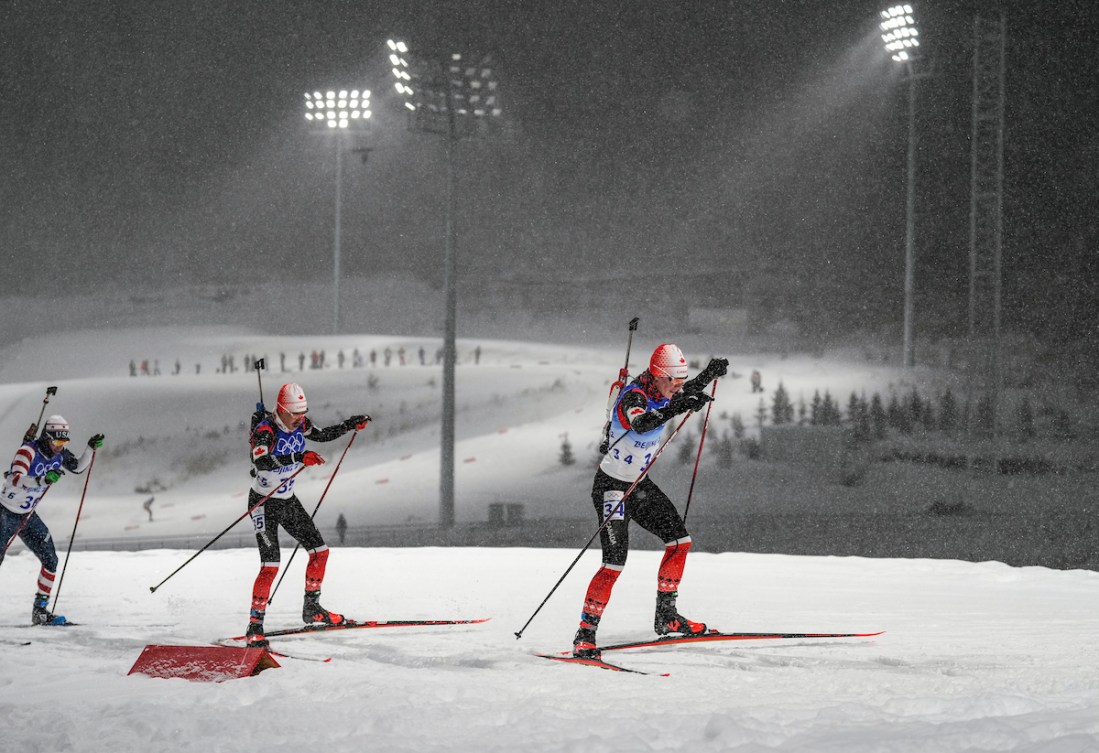 Two Canadian biathletes ski at night 