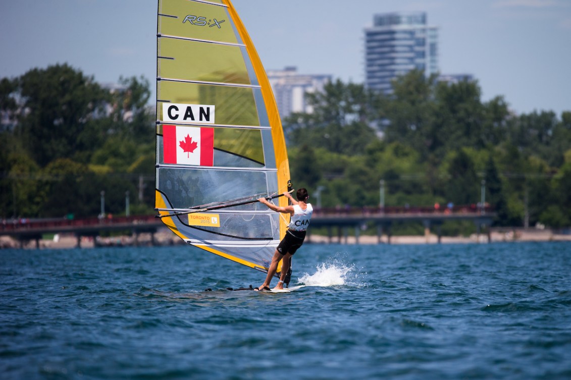 A male windsurfer on a lake in front of city skyline