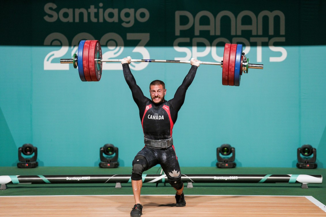A male weightlifter holds the barbell above his head 