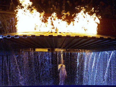 Cathy Freeman stands under the Olympic torch after lighting the flame at the opening ceremonies for the 2000 Summer Olympics in Sydney. (CP PHOTO/Kevin Frayer)