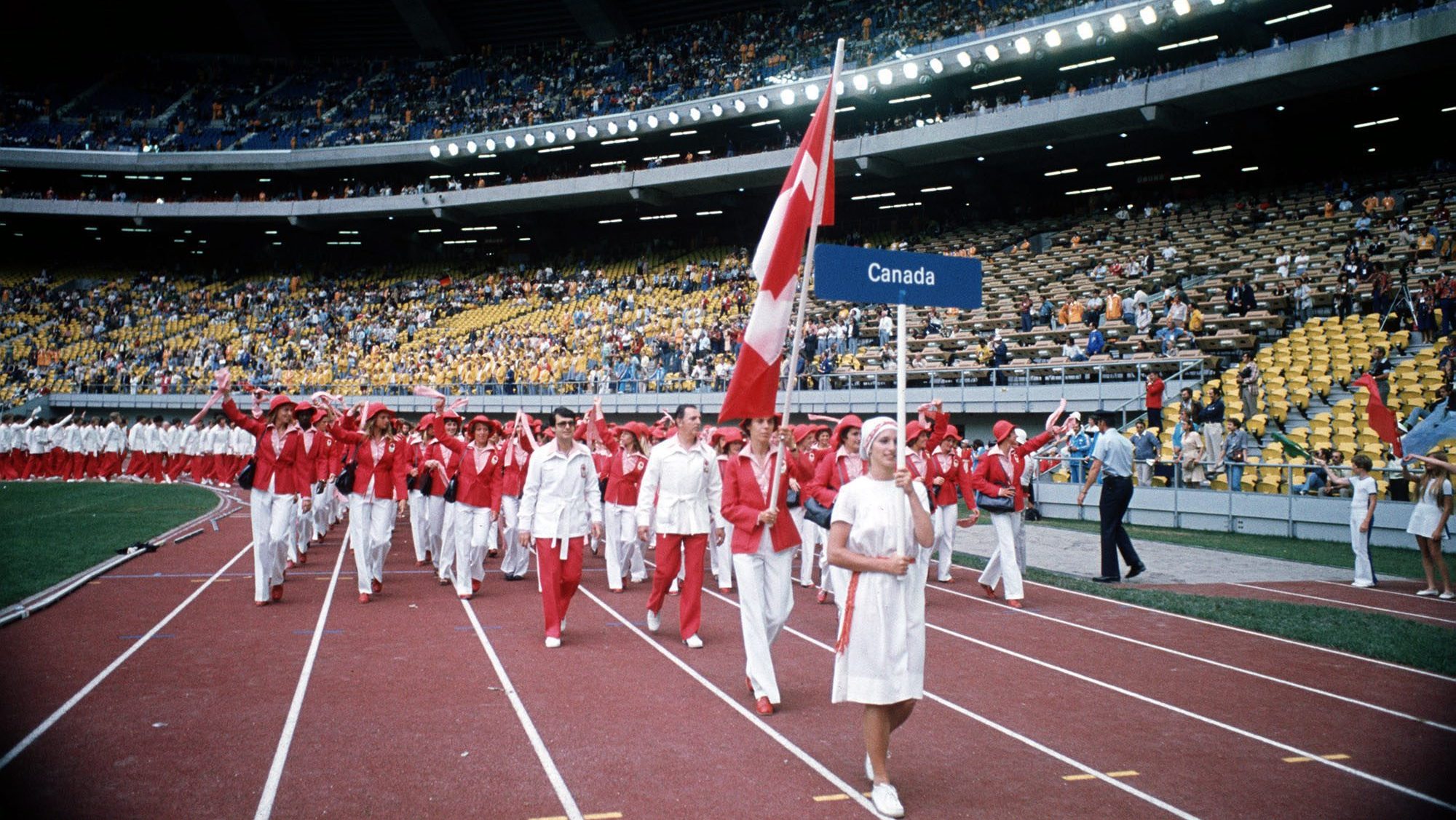 Low shot of Canadian flagbearer leading team into opening ceremony