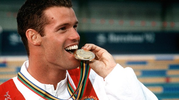 Mark Tewksbury bites his medal during the medal ceremony