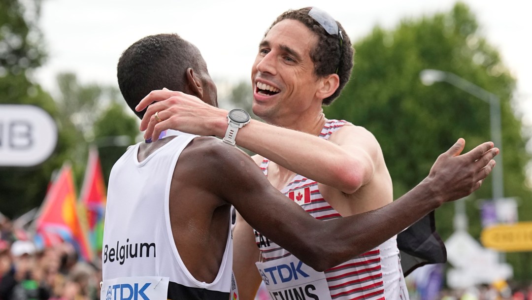 Two marathoners embrace at the finish line of the 2022 World Athletics Championships.