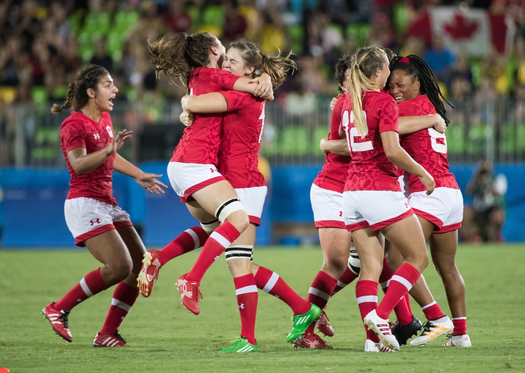 Canadian women's rugby team hug each other in celebration 
