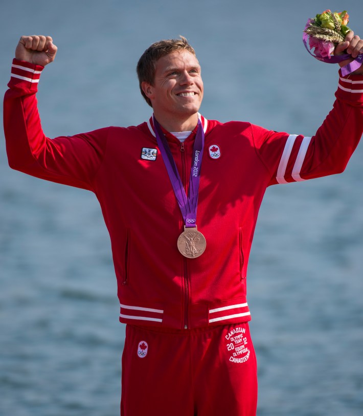 Mark de Jonge raises arms in celebration while wearing his medal