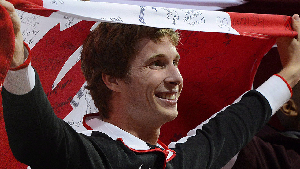 Derek Drouin holds a Canadian flag over his head