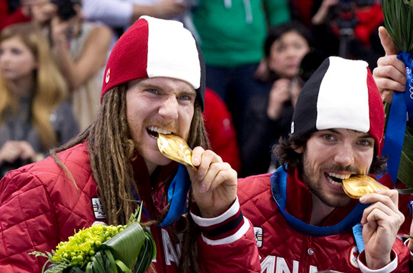 Olivier Jean and Charles Hamelin bite their 5000m relay gold medals at Vancouver 2010 THE CANADIAN PRESS/Paul Chiasson