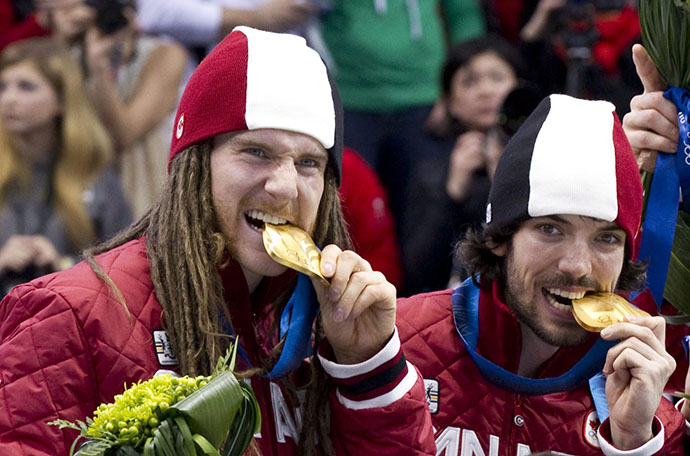 Olivier Jean and Charles Hamelin bite their 5000m relay gold medals at Vancouver 2010 THE CANADIAN PRESS/Paul Chiasson