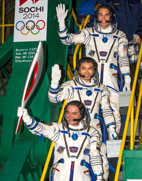 Expedition 38 Soyuz Commander Mikhail Tyurin, holding the Olympic torch, and Flight Engineers Koichi Wakata and Rick Mastracchio wave farewell prior to boarding the Soyuz TMA-11M rocket for launch. PHOTO: NASA