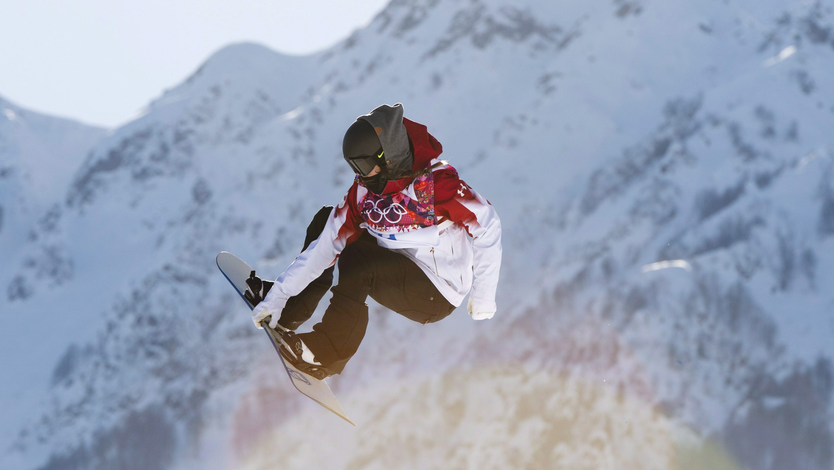 Snowboarder, Spencer O'Brien in the air with mountains in the background.