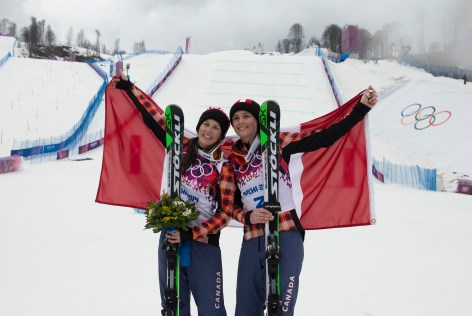 Kelsey Serwa and Marielle Thompson holding the Canadian flag behind them
