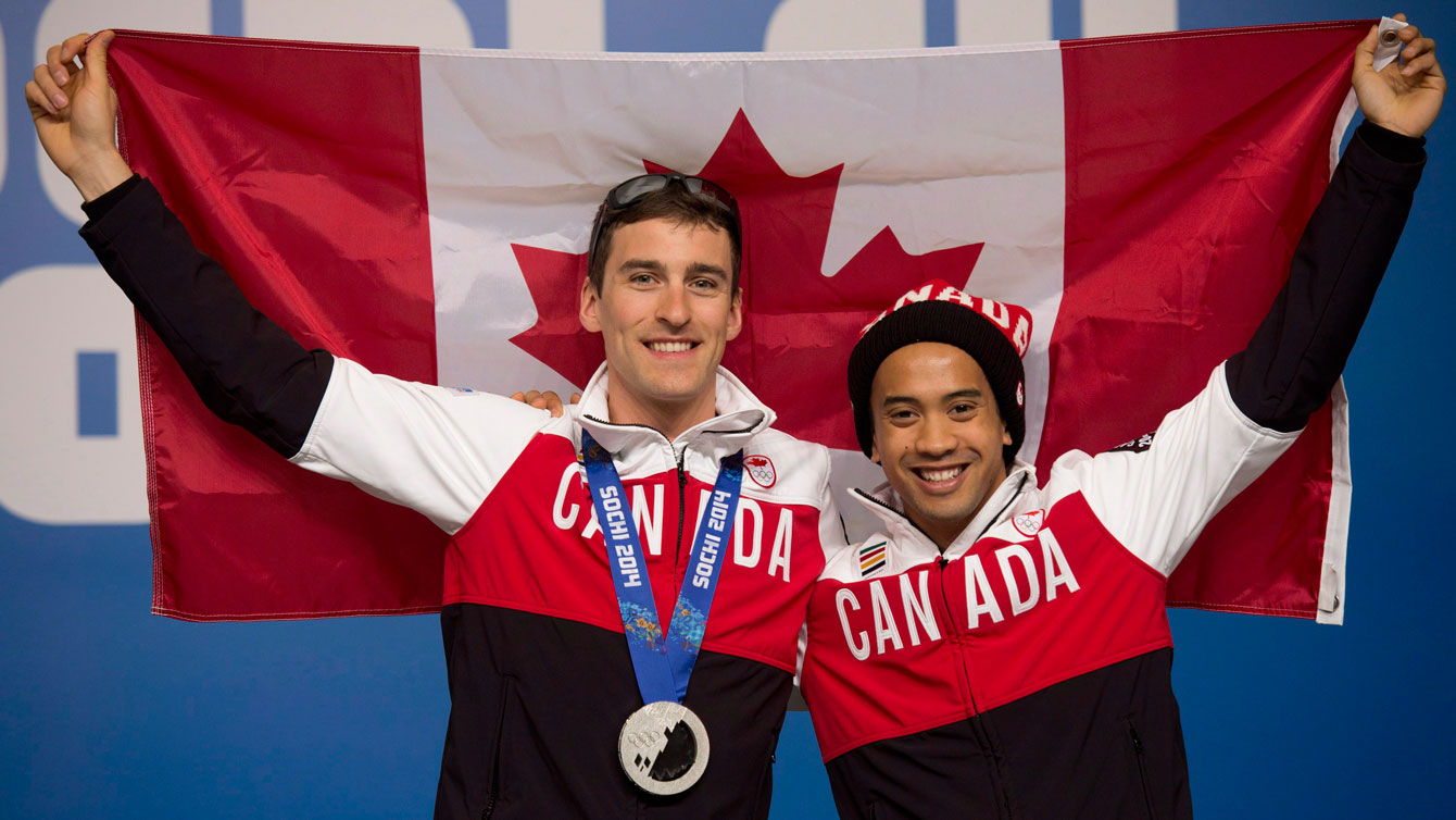 Canadian speed skaters Denny Morrison and Gilmore Junio hold up a Canadian flag following a news conference at the Sochi Winter Olympics Sunday February 16, 2014 in Sochi, Russia. THE CANADIAN PRESS/Adrian Wyld