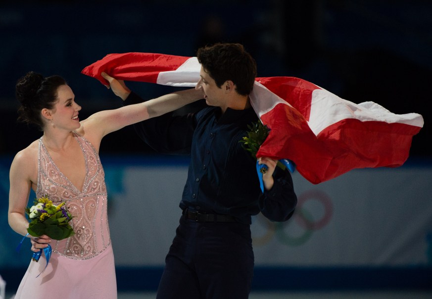 Tessa and Scott celebrating by holding the Canadian flag