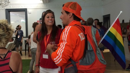 A pair of Olympic champions, Natalie Spooner (women's ice hockey) and Adam van Koeverden (canoe-kayak), chat as orange-clad AVK keeps an eye on the Netherlands World Cup match at PrideHouseTO.