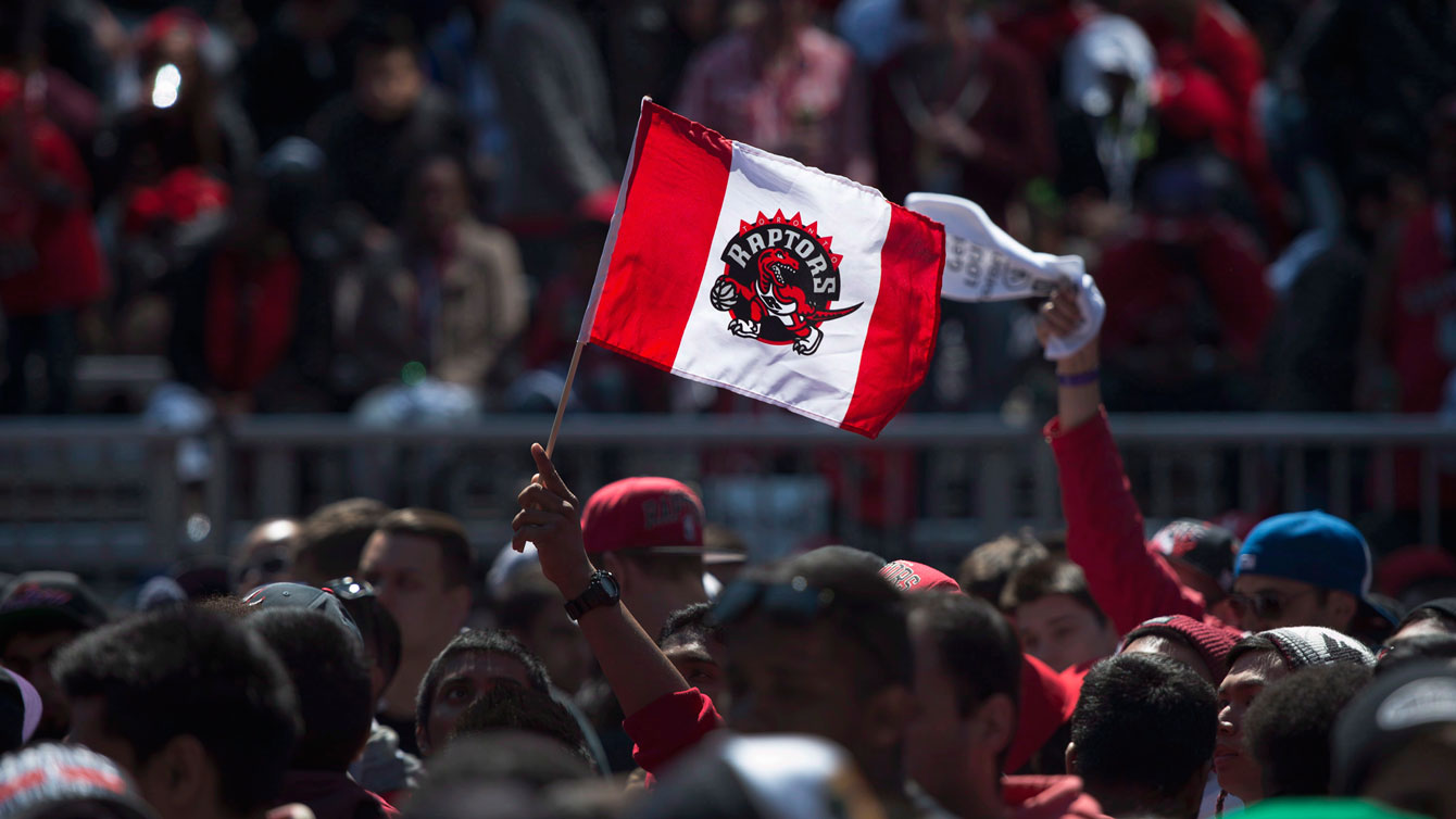 Raptors fan carries a modified Canada flag with team logo at Maple Leaf Square. 