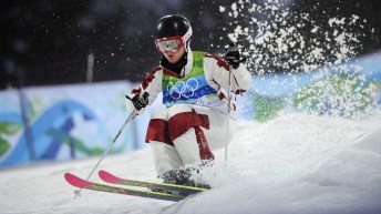 Jennifer Heil in a white snowsuit with red knee matches skis down a moguls course