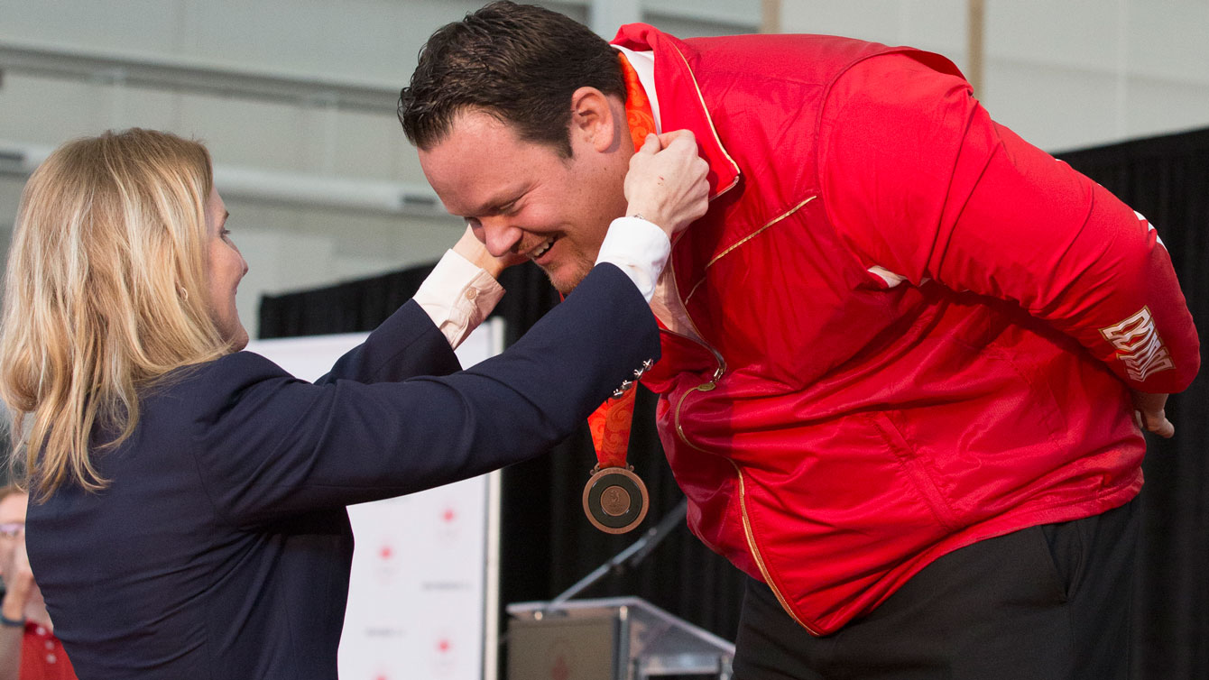 Dylan Armstrong receives his medal from Hayley Wickenheiser on behalf of the International Olympic Committee. 