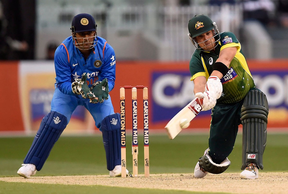 India's MS Dhoni, left, watches as Australia's Shane Watson, right, hits four runs during their One Day International cricket match in Melbourne, Sunday, Jan. 18, 2015. (AP Photo/Andy Brownbill)
