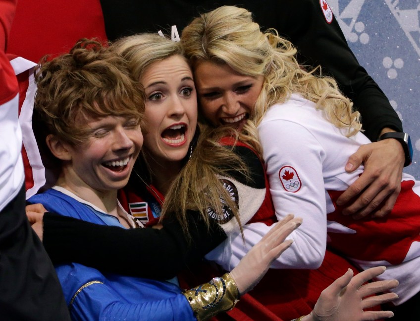 Kevin Reynolds (L) is hugged by teammates Paige Lawrence (centre) and Kirsten Moore-Towers (R) after a performance during the team event.
