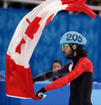 Charles Hamelin celebrates with a Canadian flag after winning 1500m gold.