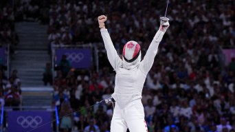 Eleanor Harvey raises both hands in celebration while wearing a Canadian flag mask