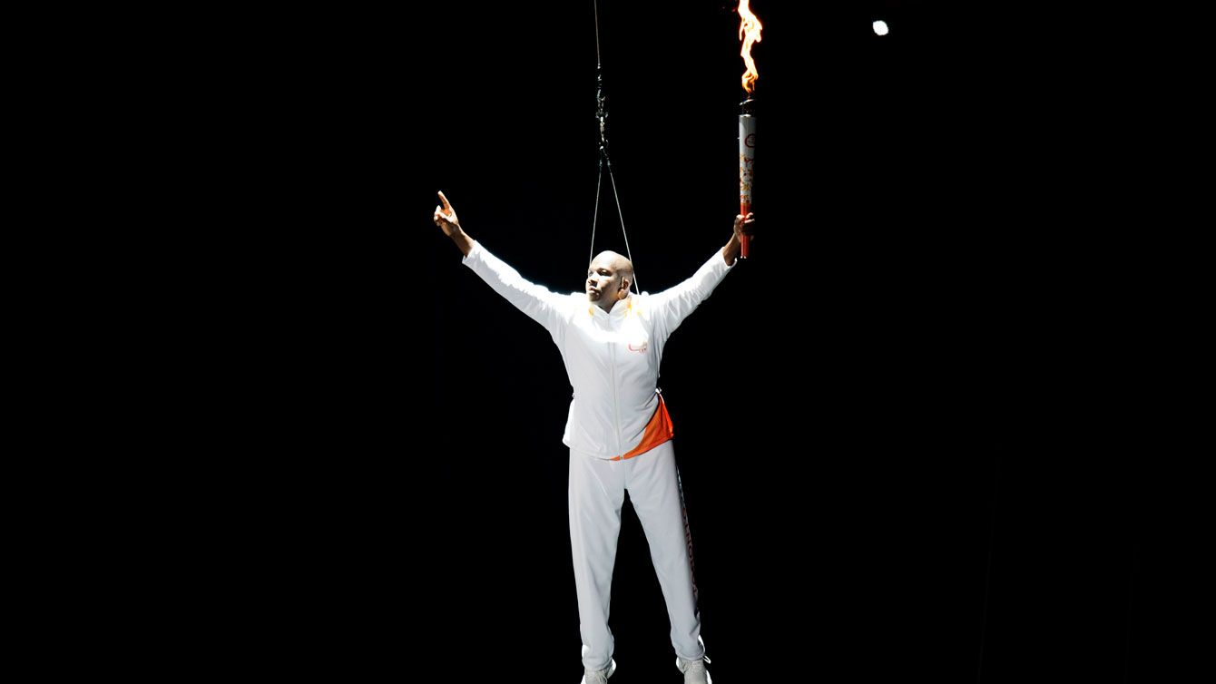 Donovan Bailey is lowered down to the Pan Am Opening Ceremony stage holding the Games' torch on July 10, 2015. 
