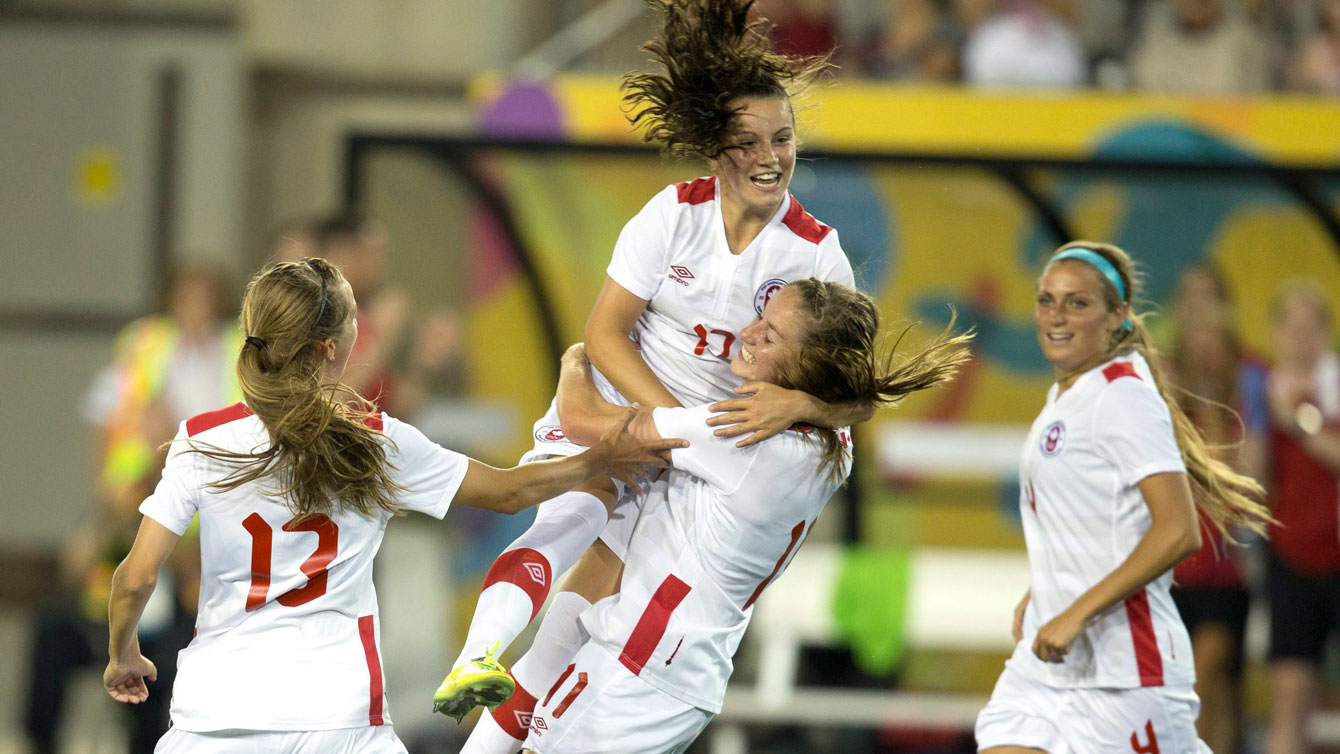 Following Janine Beckie's opening goal against Ecuador, Jessie Fleming leaps into her arms to celebrate at the Pan Am Games on July 11, 2015.