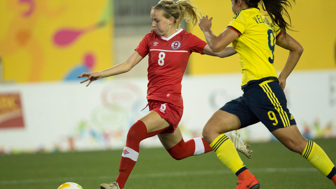 Emma Fletcher (in red, 8) dribbles before shooting against Colombia in Pan Am Games football on July 22, 2013.