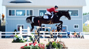 Tiffany Foster on her horse jumping over a hurdle