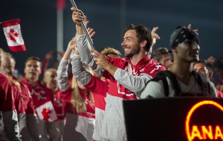 Mark Oldershaw Mark Oldershaw carries the flag in for Canada at the Opening Ceremony for TO2015. The team in its Hudson's Bay kit.