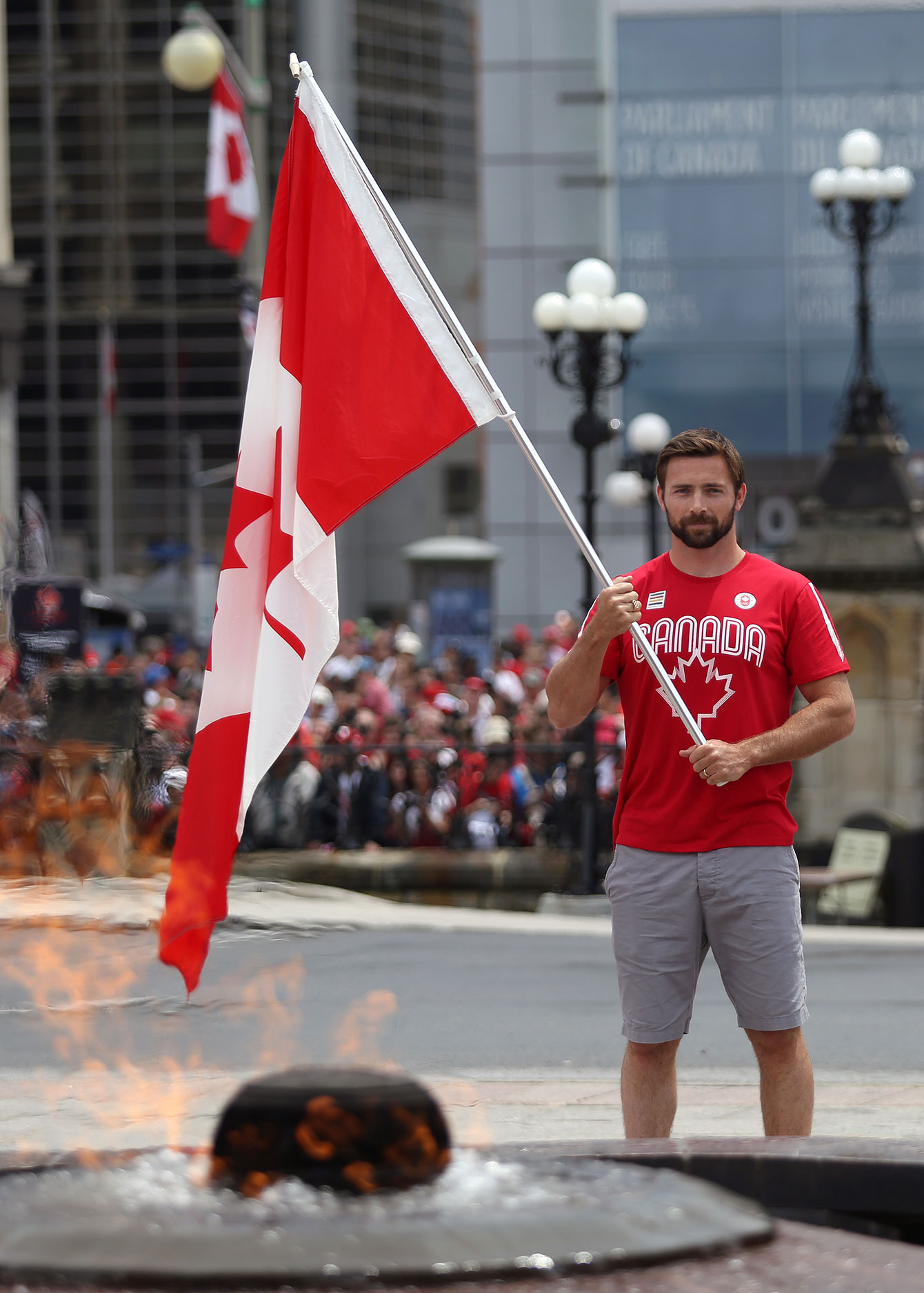 Mark Oldershaw stands with the flag in front of the Centennial Flame at Parliament Hill, on the day he was named Team Canada flag bearer for the Pan Am Games on July 1, 2015  (Greg Kolz for Canadian Olympic Team). 