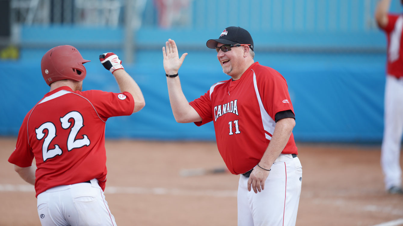 Centre-Fielder Brad Ezekiel (22) is congratulated by head coach John Stuart after hitting a home run in the bottom of the 6th inning. (Photo: Winston Chow)