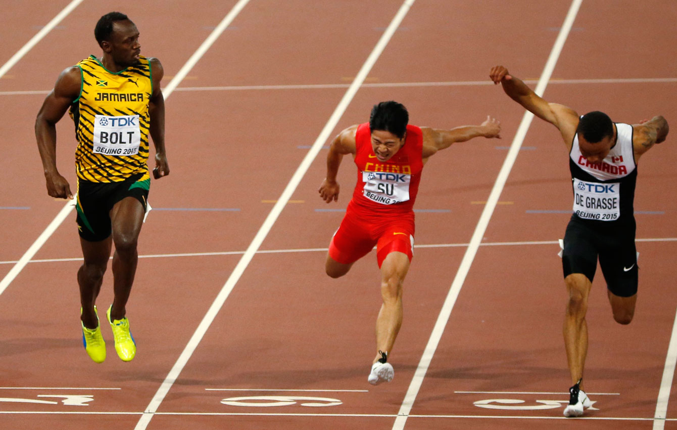 Jamaica's Usain Bolt looks over his left shoulder as Bingtian Su (China) and Andre De Grasse of Canada finish in the semifinals of the men's 100m in Beijing, China on August 23, 2015. All three men advanced to the World Championship final, with De Grasse and Bolt sharing a time of 9.96s.