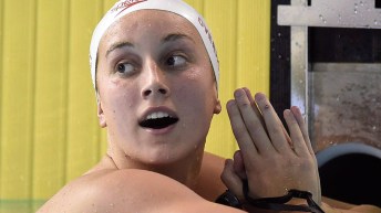 A swimmer looks at her time on the board after a race