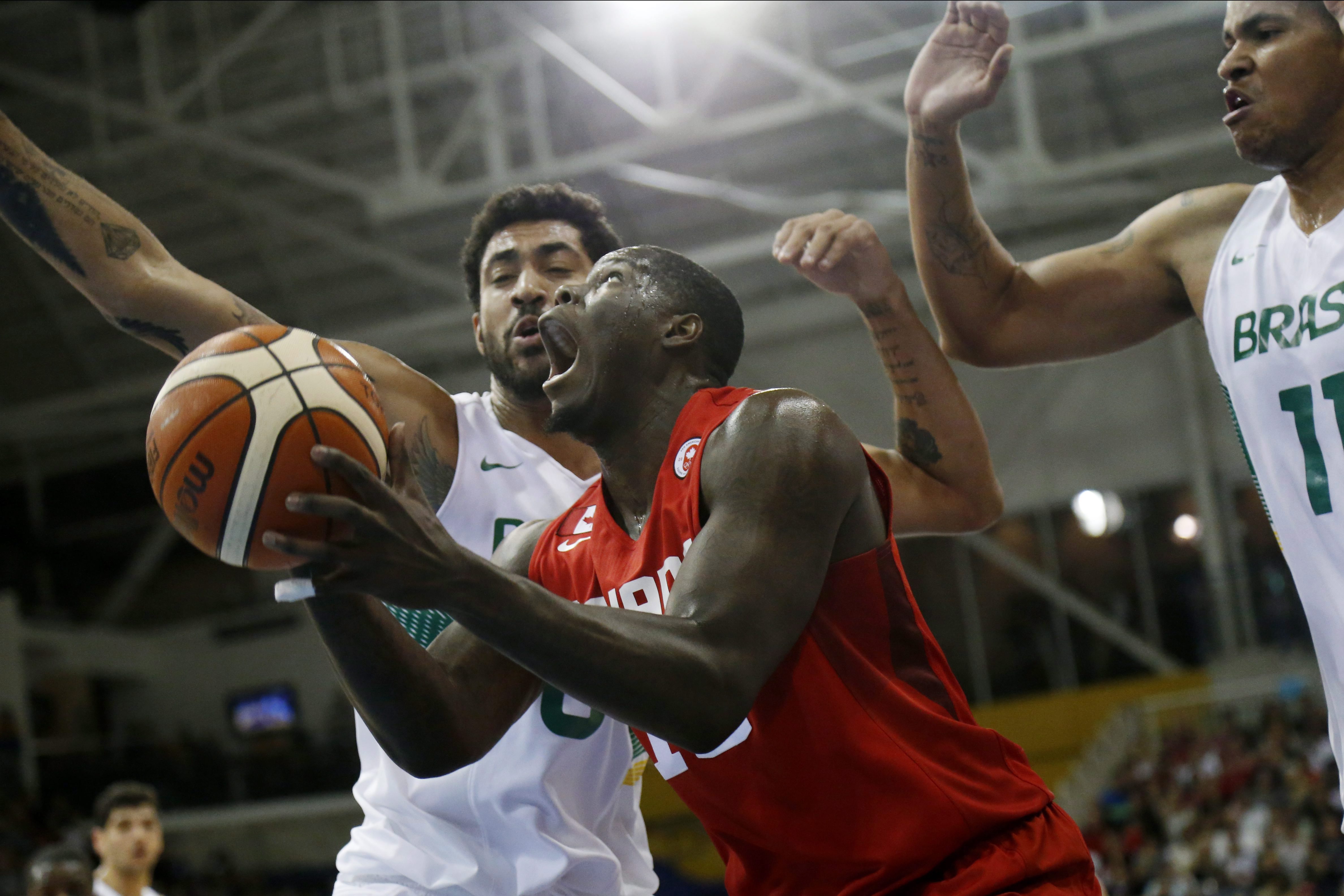 Canada's Anthony Bennett, center, looks to shoot against Brazil's Augusto Lima, left, and Rafael Hettsheimeir during the first quarter of the men's basketball gold medal game at the Pan Am Games, Saturday, July 25, 2015, in Toronto. (AP Photo/Julio Cortez)