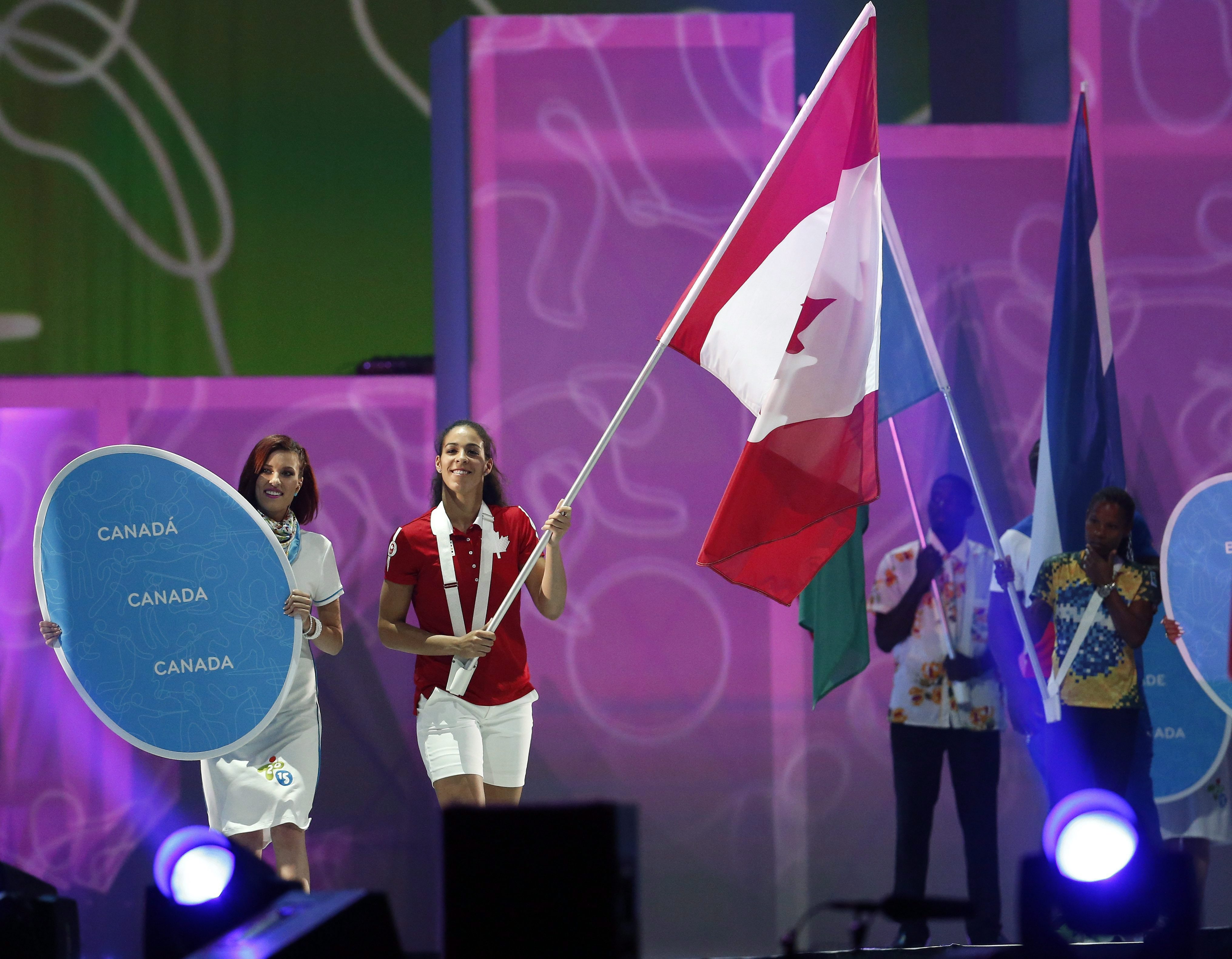 Basketball player Kia Nurse carries in the Canadian flag during the parade of nations at the closing ceremony