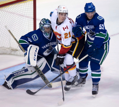 Vancouver Canucks goalie Richard Bachman, left, stops a shot from Calgary Flames' Jiri Hudler, from the Czech Republic, during NHL pre-season hockey action in Calgary, Friday, Sept. 25, 2015.