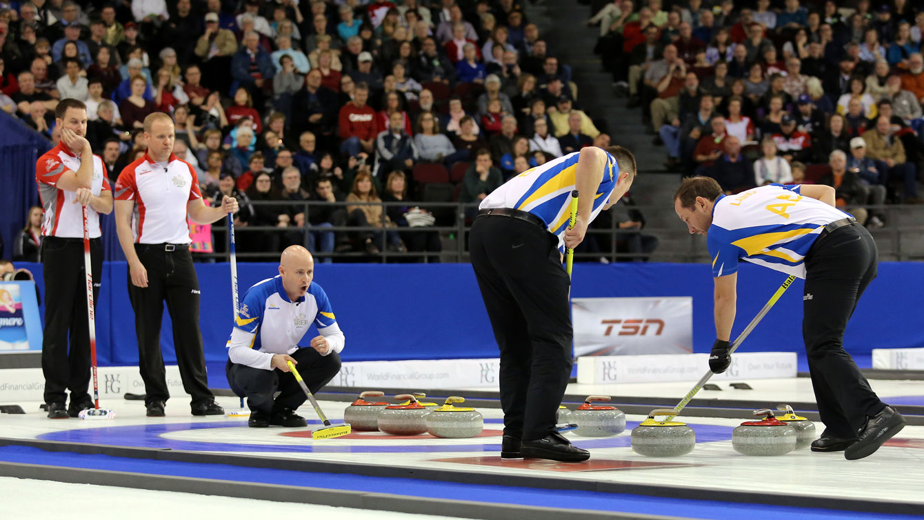 Kevin Koe (third from left) calls a stone as Brad Gushue (first from left) looks on at the Brier final on March 13, 2016 (Photo: Greg Kolz). 