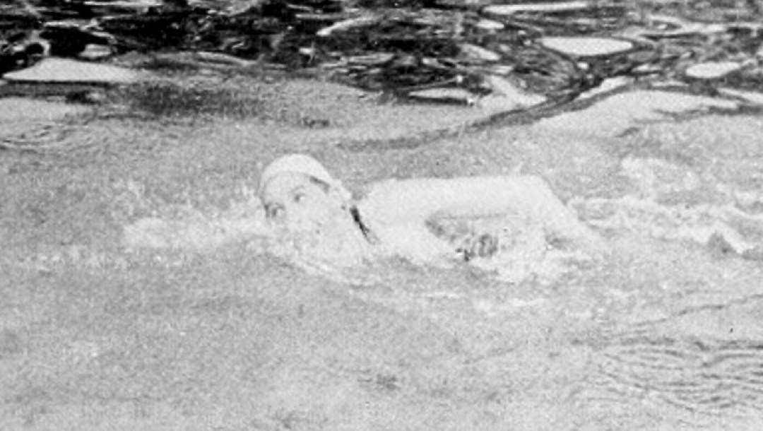 A black and white photo of a man swimming.
