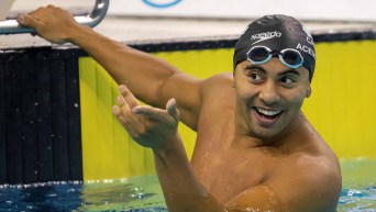 Javier Acevedo points at someone while hanging onto the wall in the pool