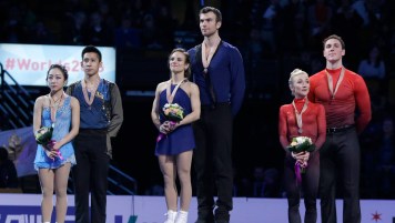 Meagan Duhamel and Eric Radford (centre) stand atop the pairs gold medal spot at the ISU Figure Skating World Championships podium ceremony on April 2, 2016.