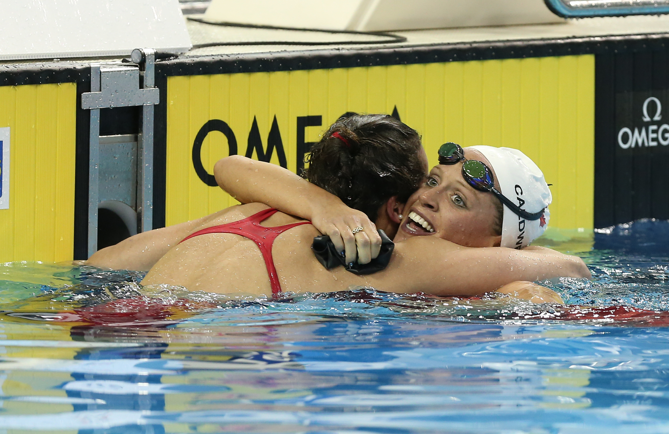 Hilary Caldwell (right) hugs a teammate after winning the 200m backstroke at Rio Trials on April 10, 2016 (Photo: Scott Grant via Swimming Canada).