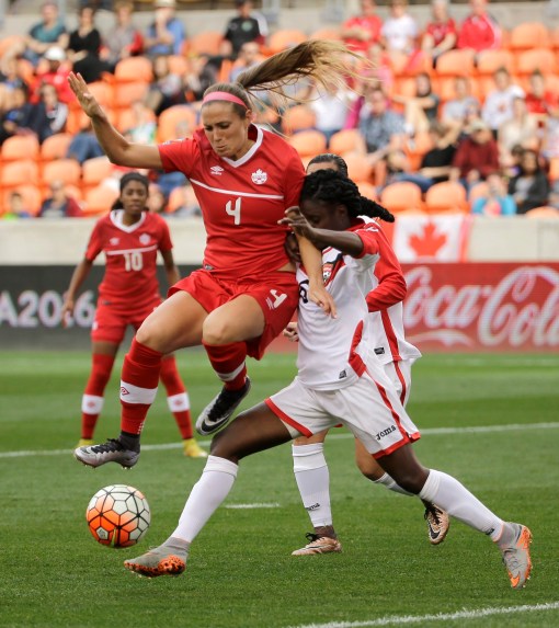 Canada's Shelina Zadorsky (4) jumps over the leg of Trinidad & Tobago's Khadidra Debesette (6) during the first half of a CONCACAF Olympic qualifying tournament soccer match Sunday, Feb. 14, 2016, in Houston. Canada won 6-0. (AP Photo/David J. Phillip)