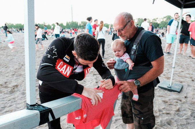 Joseph Polossifakis signs a tshirt at the Team Canada Beach Party. (Thomas Skrlj/COC)