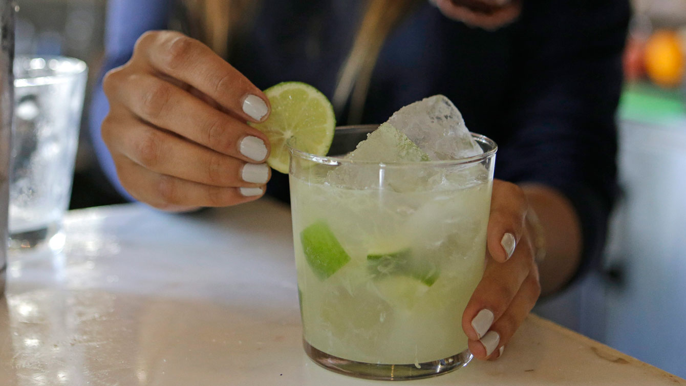 In this May 10, 2016 photo, bartender Rafaella Demelo adds a lime wedge for the final touch as a caipirinha is ready to be served at Bulla, a bar in Coral Gables, Fla.